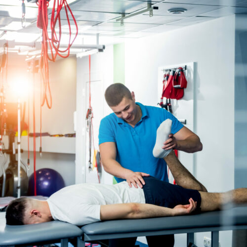 Rehabilitation therapy. Physiotherapist working with young male patient in the rehabilitation center. Treatment pain in spine